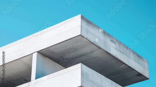 A closeup of white concrete corner apartment building with architectural detail geometric shapes on blue sky background. modern concrete building in blue