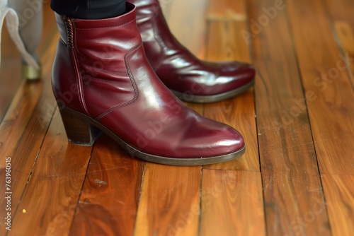 closeup of burgundy leather boots on a woman, with polished wood floor beneath