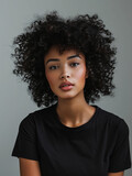A striking portrait of a beautiful woman with luscious curly hair wearing a black t-shirt against a muted backdrop