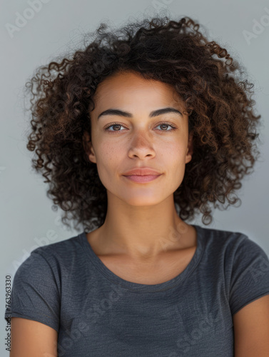 This is a portrait of a relaxed woman with a gentle smile  naturally curly hair  and a casual gray top against a simple background