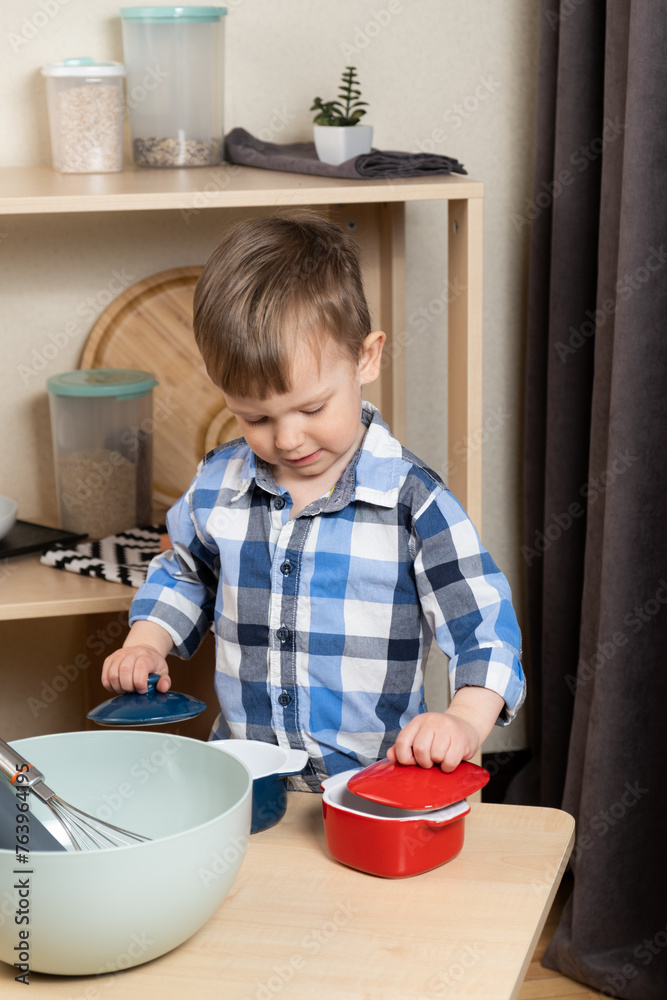 A two-year-old boy cooking in the kitchen, making dough. Cooking and kids A two-year-old boy cooking in the kitchen, making dough. Cooking and kids