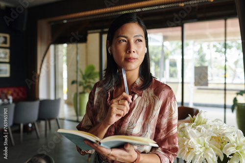 Fotografi Portrait of pensive businesswoman with planner standing in her restaurant