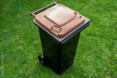 Braune Biotonne steht auf grüner Wiese