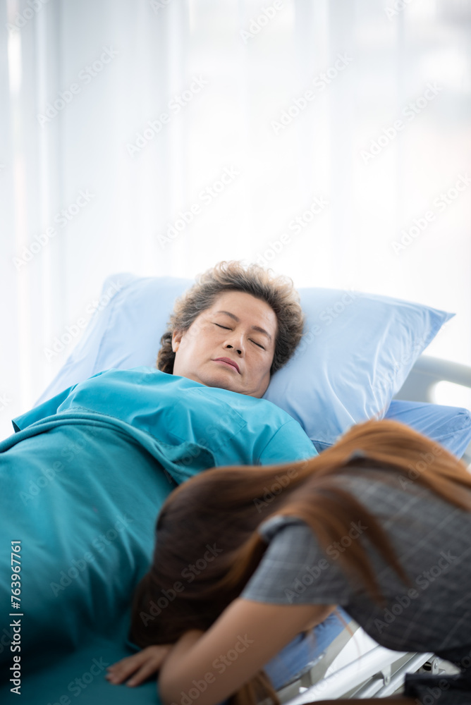 Asian senior or elderly old woman patient lie down handle the rail bed with hope on a bed in the hospital, old lady is sick and lying on the patient bed, recovering on saline drip solution Asian senior or elderly old woman patient lie down handle the rail bed with hope on a bed in the hospital, old lady is sick and lying on the patient bed, recovering on saline drip solution