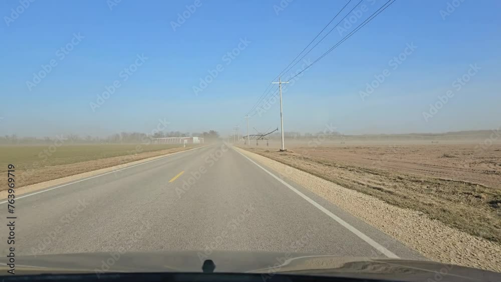 Driving on freeway through small sandstorm created from exposed plowed farm fields on each side of the road after days of drought sunny warm days in the winter season. Driving on freeway through small sandstorm created from exposed plowed farm fields on each side of the road after days of drought sunny warm days in the winter season.