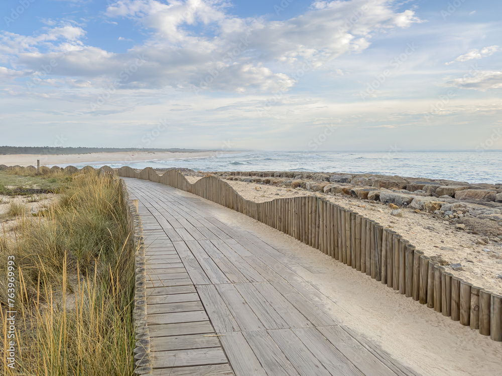 A wood pedestrian walkways, build over a sand dune that is used to give beach access in Furadouro beach, glows at sunset. Ovar, Aveiro, Portugal, Europe