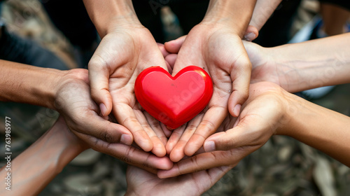 Hands holding small red heart. United diversity or multi-cultural partnership in a group	 photo