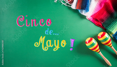 Cinco de Mayo holiday background made from maracas, mexican blanket stripes or poncho serape on green background. photo