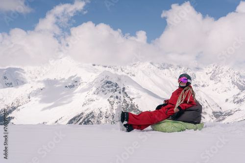 Woman freerider snowboarder sitting on the slope relaxing while skiing off piste