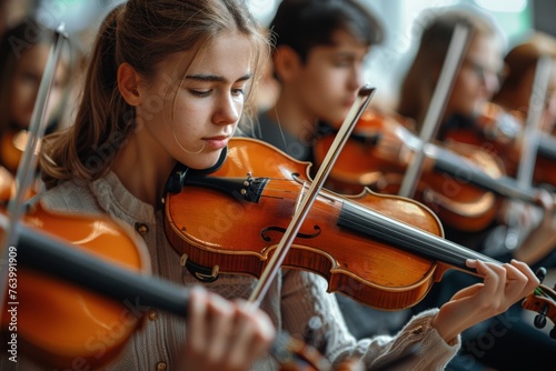 Young violinist concentrating intensely while performing in an orchestra setting photo