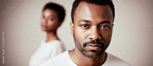 ritratto primo piano di giovane uomo di colore, luce naturale, sfondo sfuocato con figura femminile photo