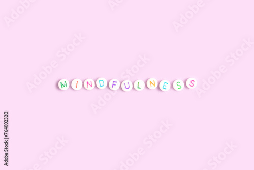 Mindfulness. Word made of white round beads with multicolored letters on a purple background.