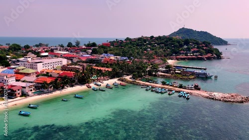 Aerial view of Haad Rin District and Haad Rin Pier (Haad Rin Queen Ferry), Koh Phangan, Thailand. Drone travelling from the sea towards the beach.  photo