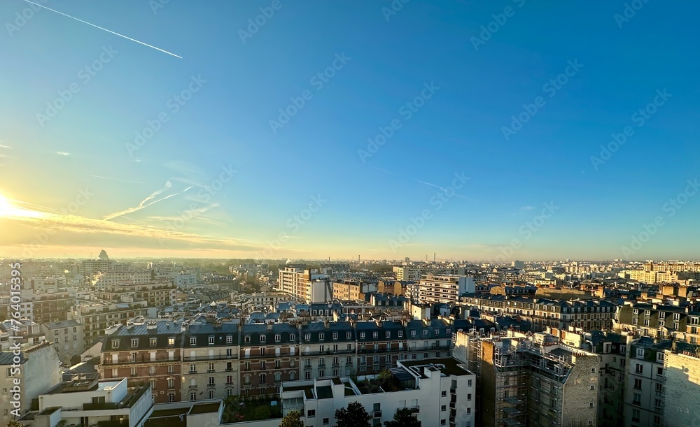 Golden Sunrise Over Parisian Rooftops with Clear Skies and Contrails