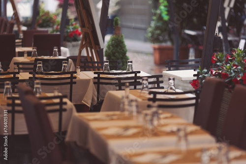 Beautiful tables in a street cafe in rainy day, Milano, Italy. Street view of a coffee terrace with tables and chairs in europe.  photo