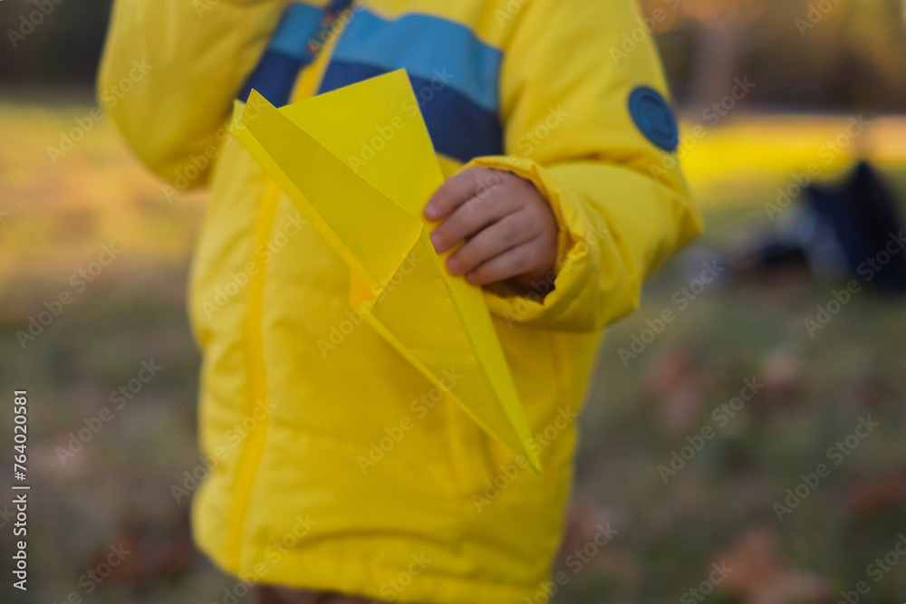 A blond boy plays with paper airplanes in the park, radiating joy and excitement during outdoor weekend fun. It's a perfect family getaway filled with laughter and enjoyment. A blond boy plays with paper airplanes in the park, radiating joy and excitement during outdoor weekend fun. It's a perfect family getaway filled with laughter and enjoyment.