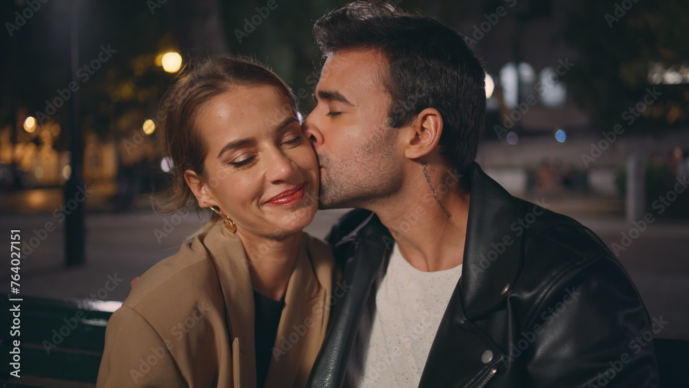 Gentle guy kissing girl cheek on date closeup. Smiling sweethearts resting park