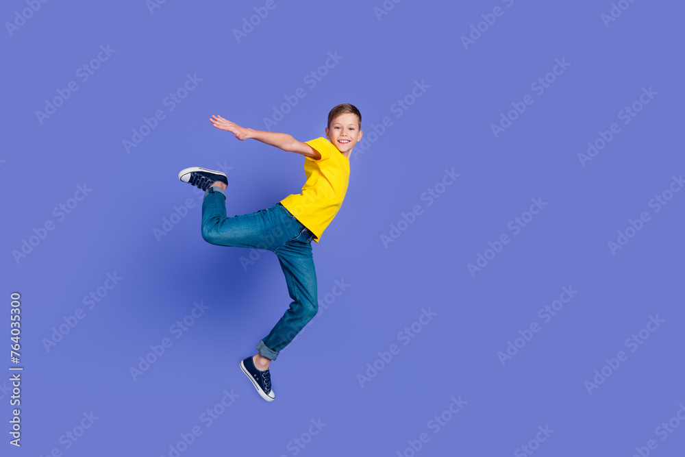 Full length photo of good mood nice boy wear stylish yellow clothes open hands fly air isolated on violet color background
