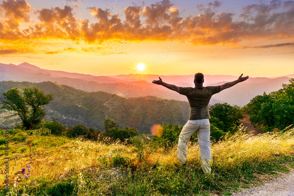 rejoicing man with beautiful scenic mountain sunset landscape on background. happy man watching amazing evening sunset rejoicing man with beautiful scenic mountain sunset landscape on background. happy man watching amazing evening sunset