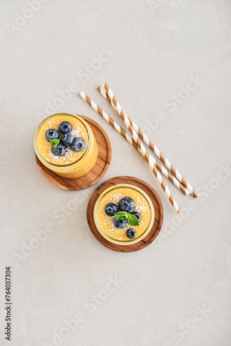 Refreshing and healthy mango smoothie with coconut flakes and fresh blueberries