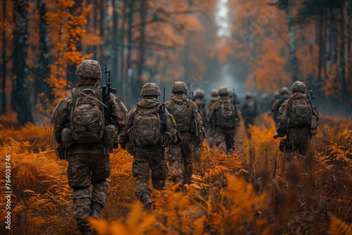 A squadron of soldiers marching in uniform through an autumnal forest, illustrating teamwork and tactical deployment photo