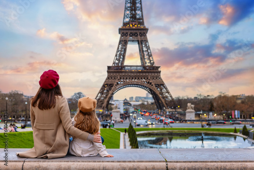 Family city travel concept with a mother and her daughter looking at the beautiful sunset view of the Eiffel Tower in Paris, France photo