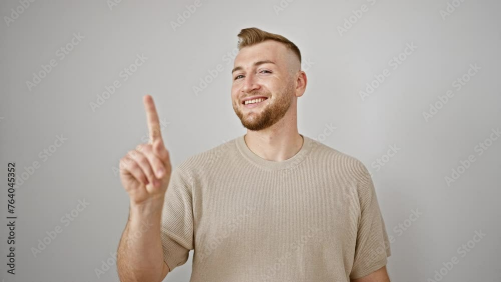 A young, bearded man gestures no with his finger against a white wall A young, bearded man gestures no with his finger against a white wall
