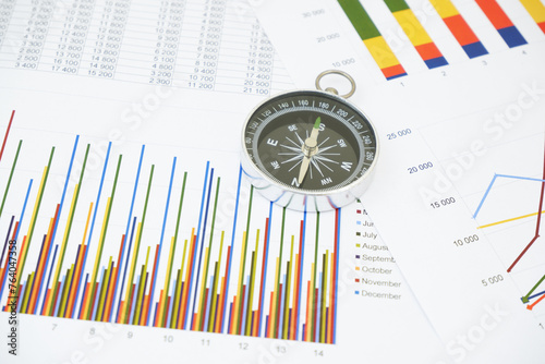 Round compass on papers with financial data.