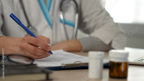 Female doctor writing on clipboard at desk in hospital
