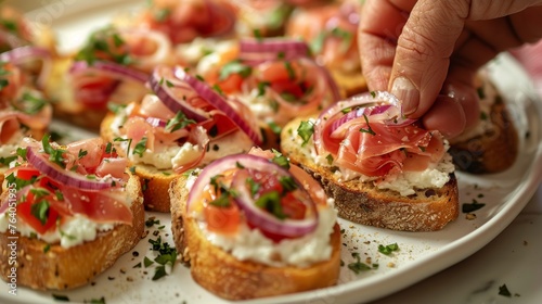 Close-up of hand-decorated ciabatta bruschetta topped with cream cheese, prosciutto, and red onion, ready to serve