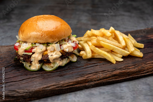 variety of homemade beef burgers with onion cucumber dressings tomato chedar cheese lettuce mayonnaise mustard ketchup barbecue with potato bun and french fries on wooden board photo