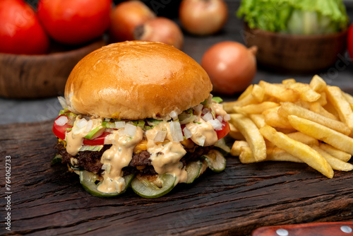 variety of homemade beef burgers with onion cucumber dressings tomato chedar cheese lettuce mayonnaise mustard ketchup barbecue with potato bun and french fries on wooden board photo