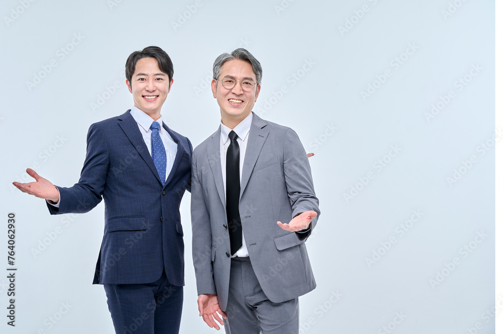 A young office worker man wearing a suit and glasses and a middle-aged man are posing with a variety of confident expressions together. A young office worker man wearing a suit and glasses and a middle-aged man are posing with a variety of confident expressions together.