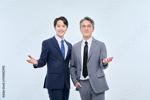 A young office worker man wearing a suit and glasses and a middle-aged man are posing with a variety of confident expressions together.