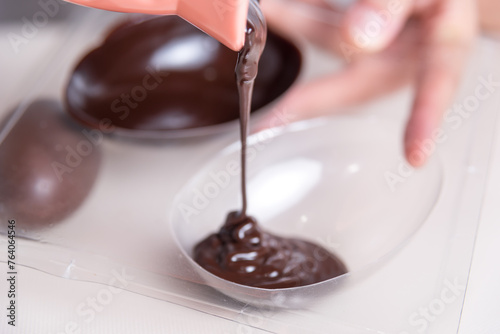 making handmade easter eggs, close up of liquid chocolate, molds
