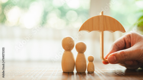 Quadro su tela Parent and child model holding an umbrella on a wooden table, concept of health