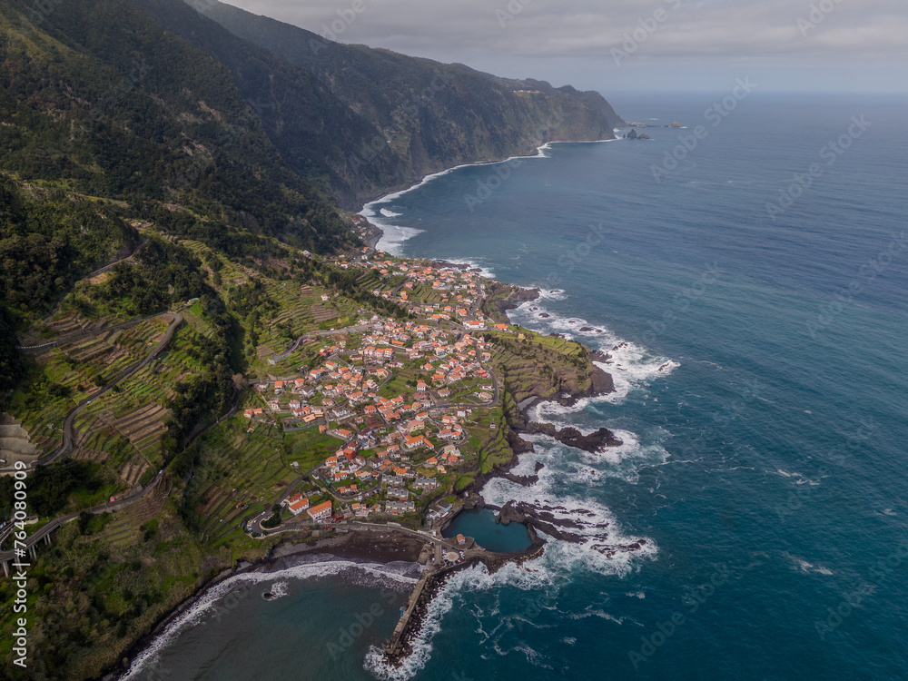 Aerial view of Seixal, a little village by the ocean with waves and surrounded with incredible mountains on the island of Madeira, Portugal.
