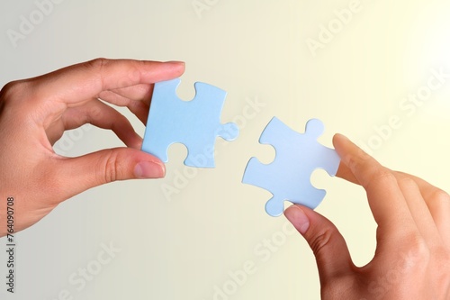 People hands connecting colored puzzles.