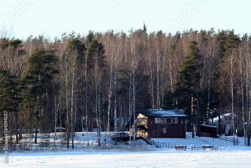 house on the bank of a frozen river in the forest