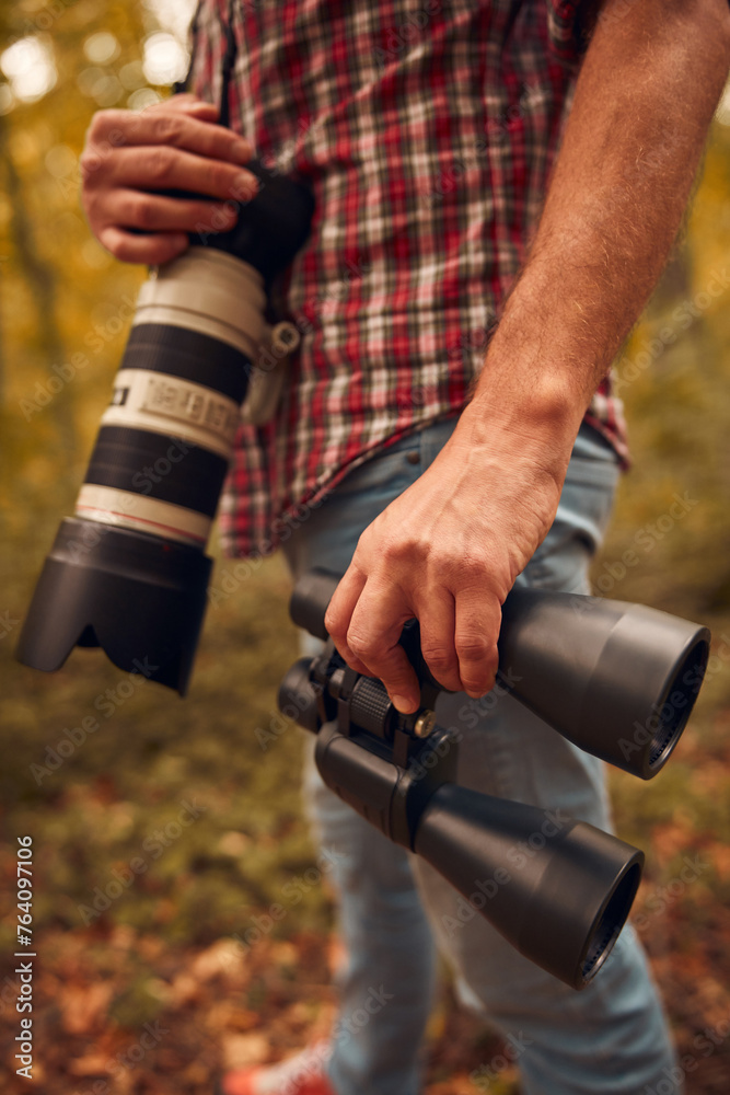 Naklejka premium Man using binoculars and camera for birdwatching and other observing animals in nature.