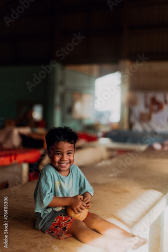 Smiling child sitting indoors with sunlit background