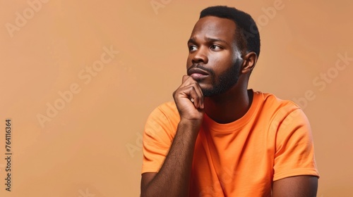 Contemplative young man with a thoughtful expression, looking upward in curiosity against a warm orange backdrop - AI generated.