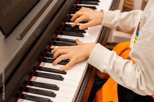 Close-up of a boy's hands on the keys of a piano, child learning to play piano photo