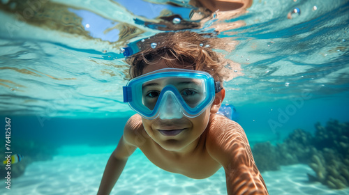 Summer fun. Underwater boy snorkeling on a tropical beach, looking at the camera and smiling.