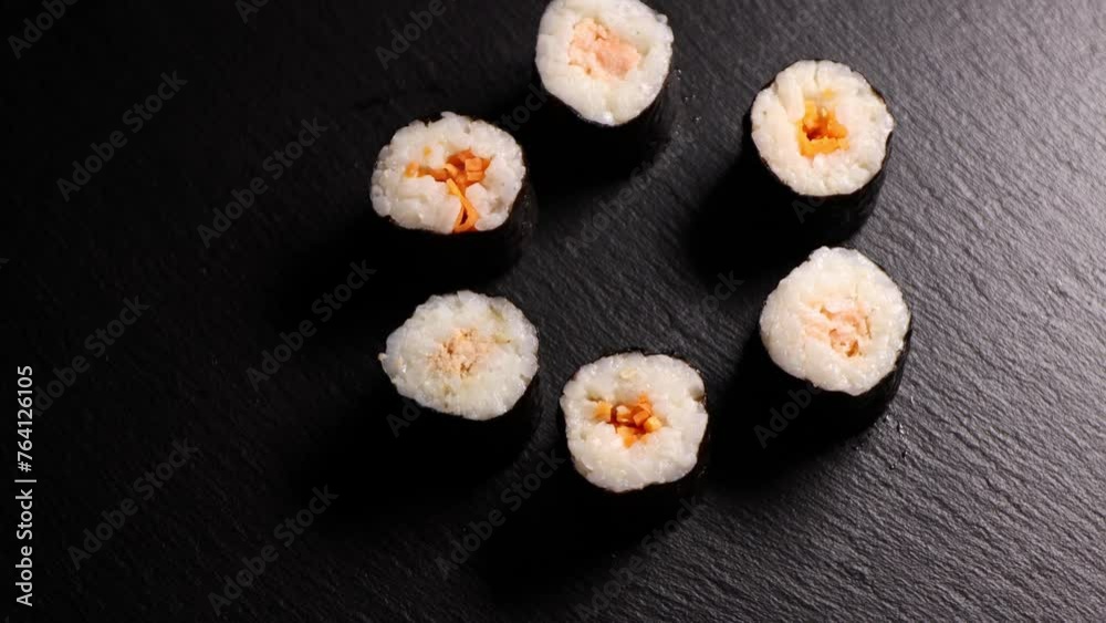 sushi on a black plate. Spinning hosomaki sushi rolls, top view sushi on a black plate. Spinning hosomaki sushi rolls, top view