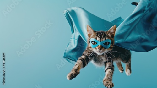 Adventurous ginger cat heroically posing with a flowing cape and mask against a sky-blue background, embodying whimsical pet fun - AI generated © qntn