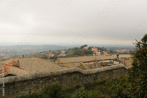 Mura con tetti e tegole della Rocca dei Papi con vallata e cielo nuvoloso
