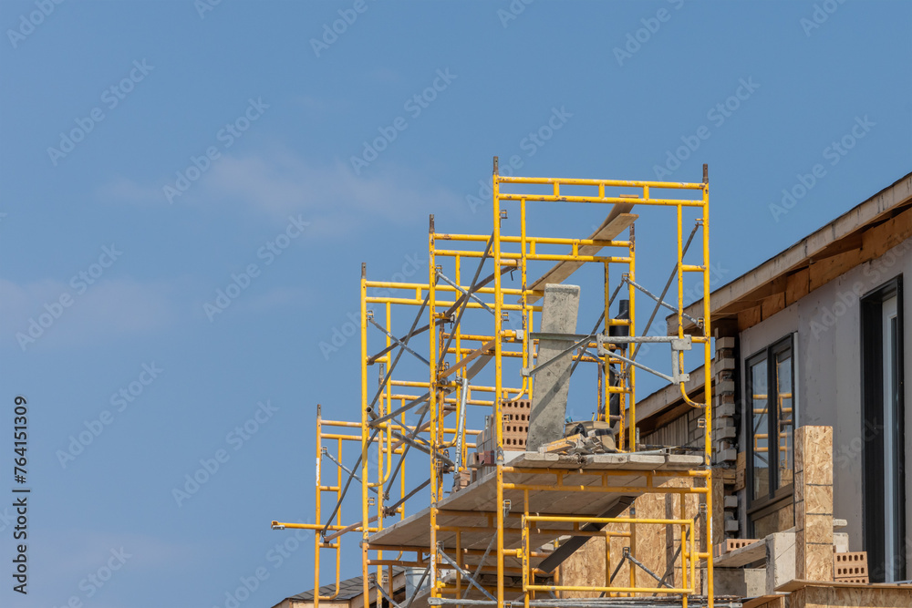 Yellow metal scaffold at a residential construction site ready for brick layers Yellow metal scaffold at a residential construction site ready for brick layers