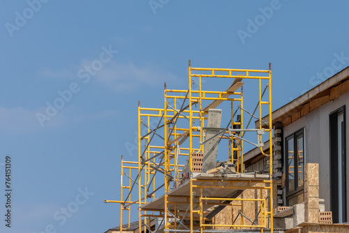 Yellow metal scaffold at a residential construction site ready for brick layers
