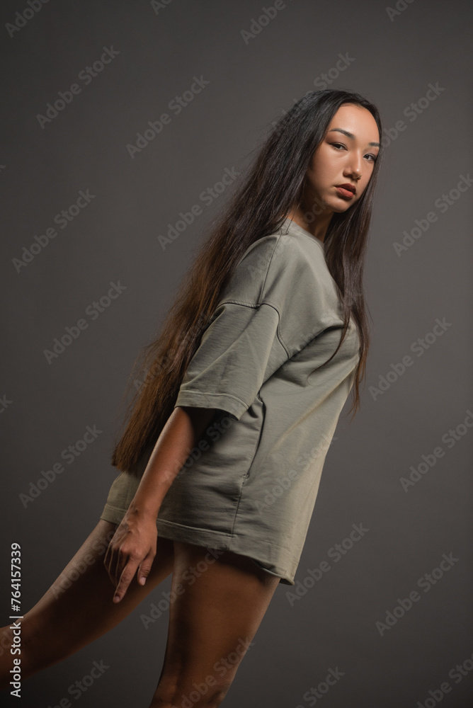 Beautiful young asian girl posing on the gray background. Beautiful young asian girl posing on the gray background.